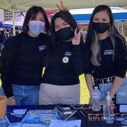 3 students smiling behind a mask