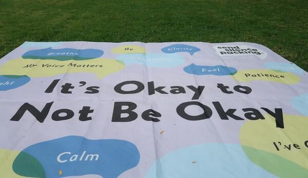 Banner laying on grass that states "It's okay to not be okay" 